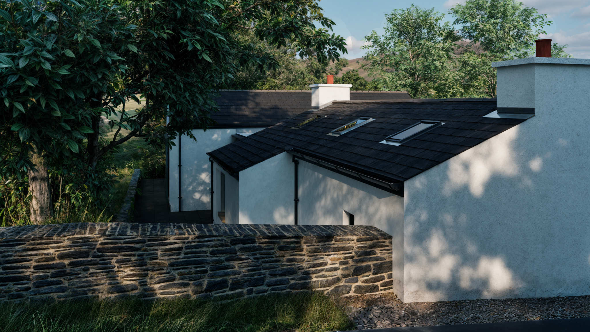 House Extension 6 Donegal Architect - Image19- Image shows an extension to a 19th century Donegal cottage featuring smooth white walls and slate roof and a large patio garden area. House is surrounded by trees and grass.