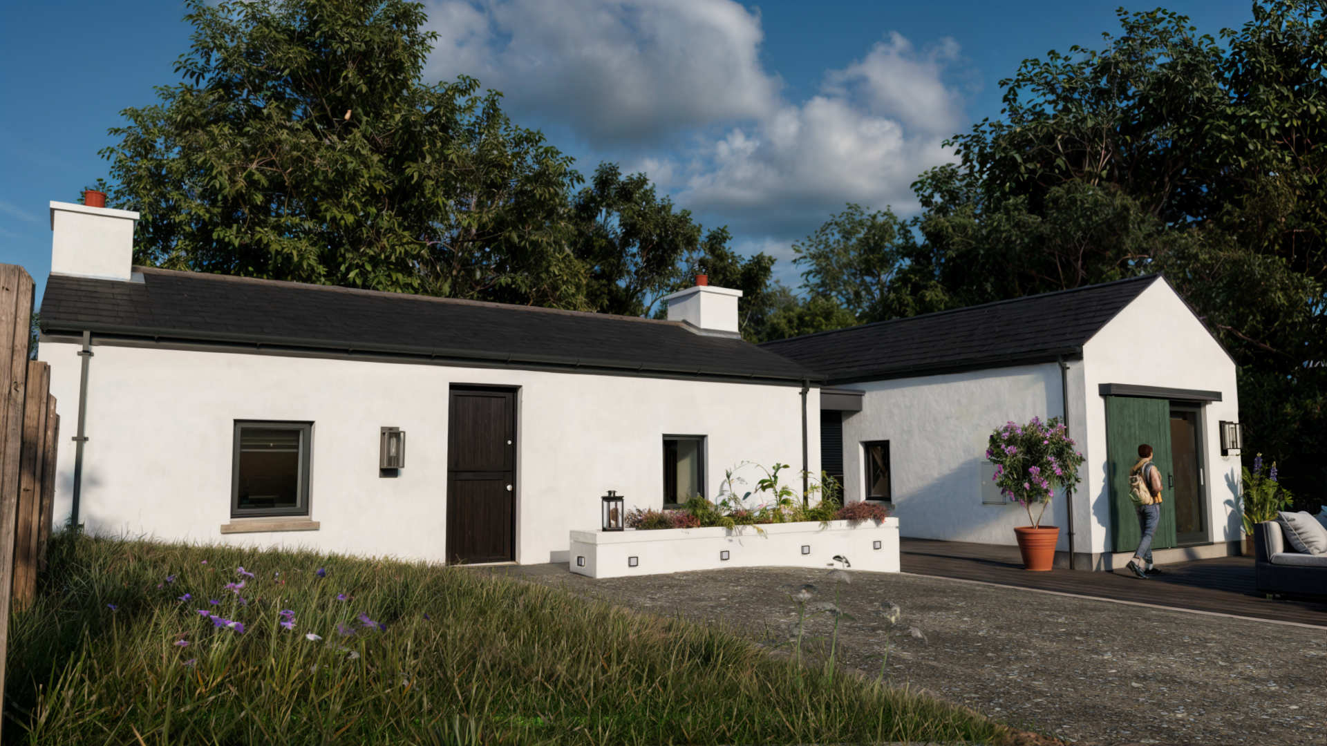 House Extension 6 Donegal Architect - Image19- Image shows an extension to a 19th century Donegal cottage featuring smooth white walls and slate roof and a large patio garden area. House is surrounded by trees and grass.