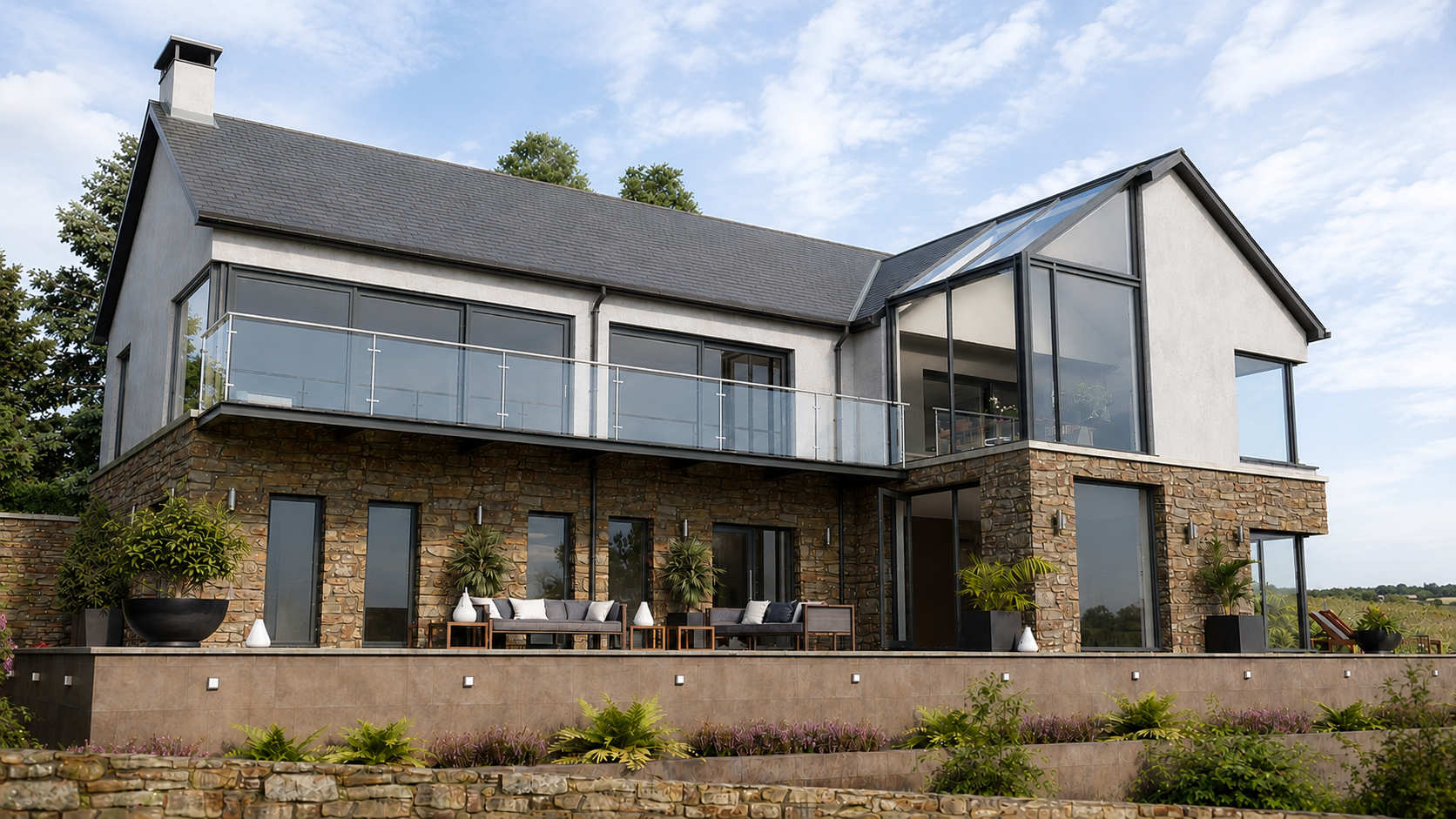 Contemporary house in Donegal with natural stone walls, white render, slate roofs and large glazed gable overlooking the landscape.